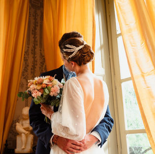 Mariée coiffée d’un chignon bas avec un accessoire en porcelaine froide, créé à la main dans notre atelier parisien. Un bijou de tête élégant et sur mesure.