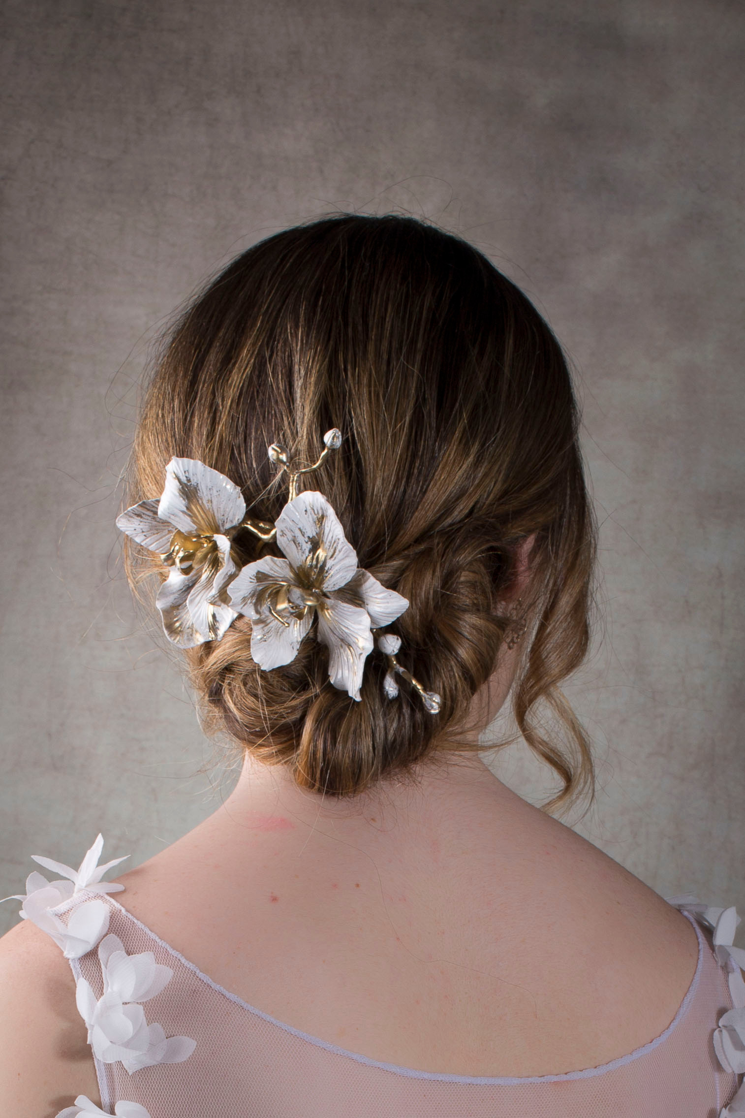 Accessoire de chignon à l’arrière en porcelaine froide blanche et dorée, composé de fleurs sculptées, porté sur un chignon ba