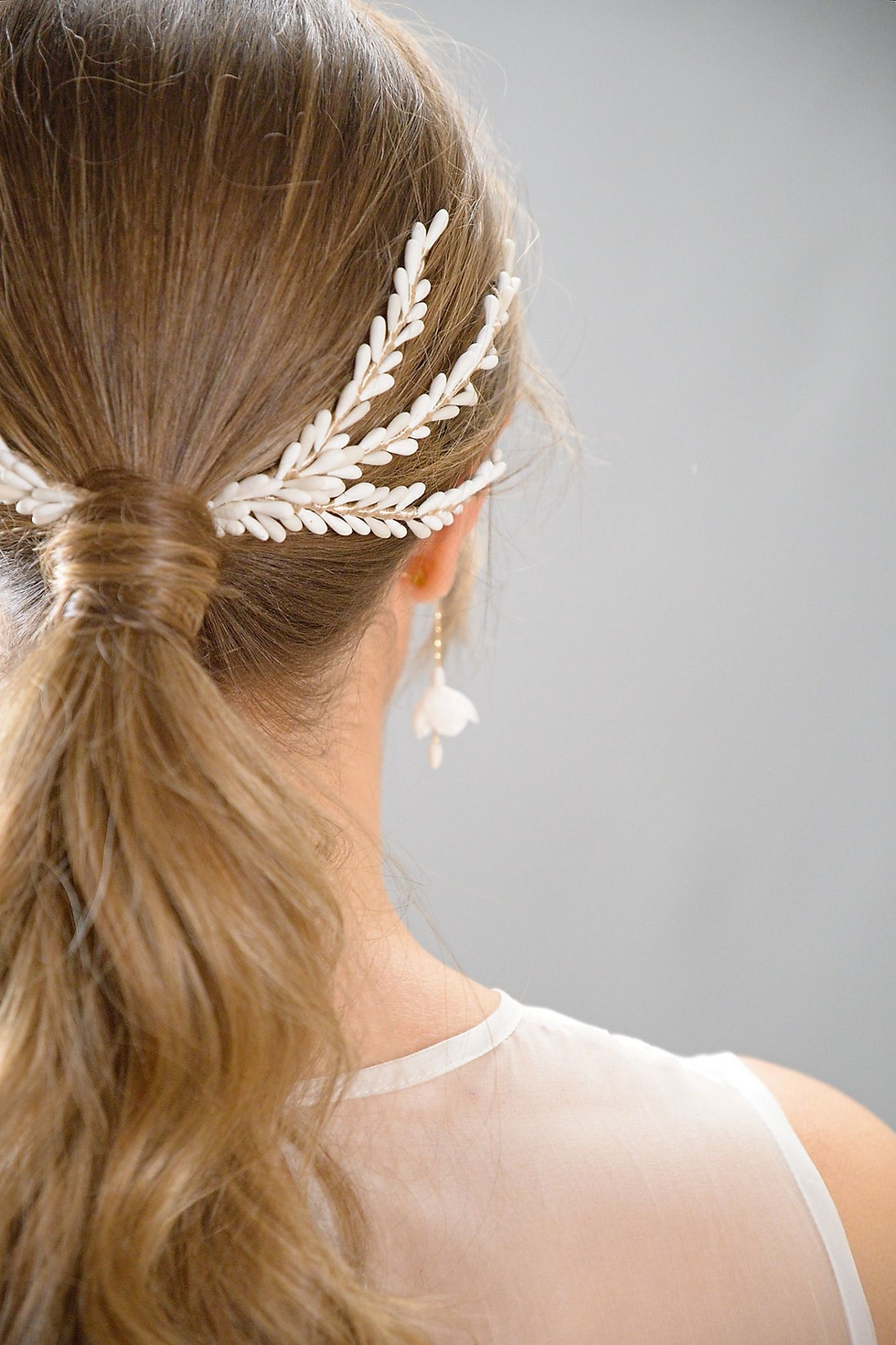 Accessoire de chignon porté à l’arrière, composé d’éléments blancs en porcelaine froide disposés symétriquement autour d’un c