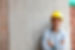 minority construction worker leaning against a wall smiling