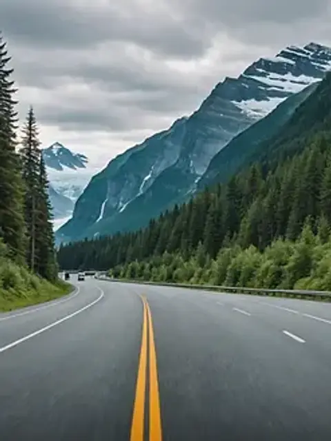 Wide angle view of the Glacier Highway lined with towering trees and coastal scenery