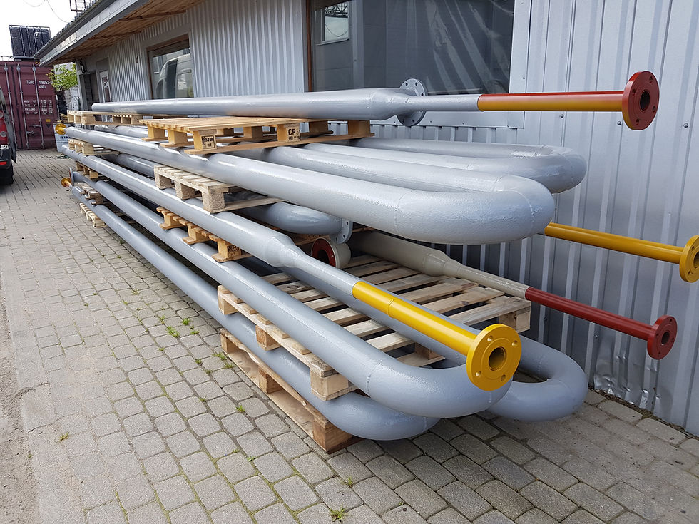Batch of coated U-shaped tube assemblies stacked on pallets outside the workshop.