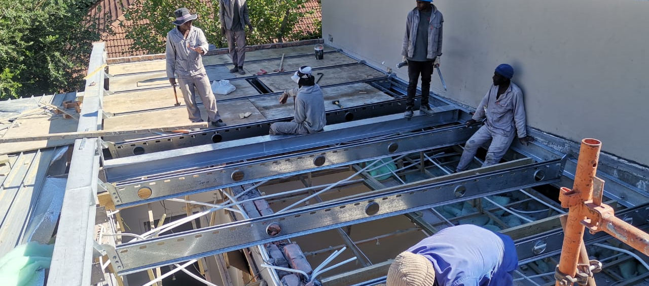 Construction workers building a roof structure on a sunny day at the site.