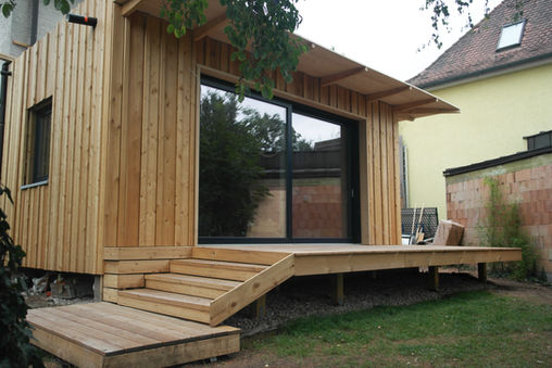 Anbau in Holzrahmenbauweise mit aufgeständerter Holzterrasse und Fassade aus Lärche