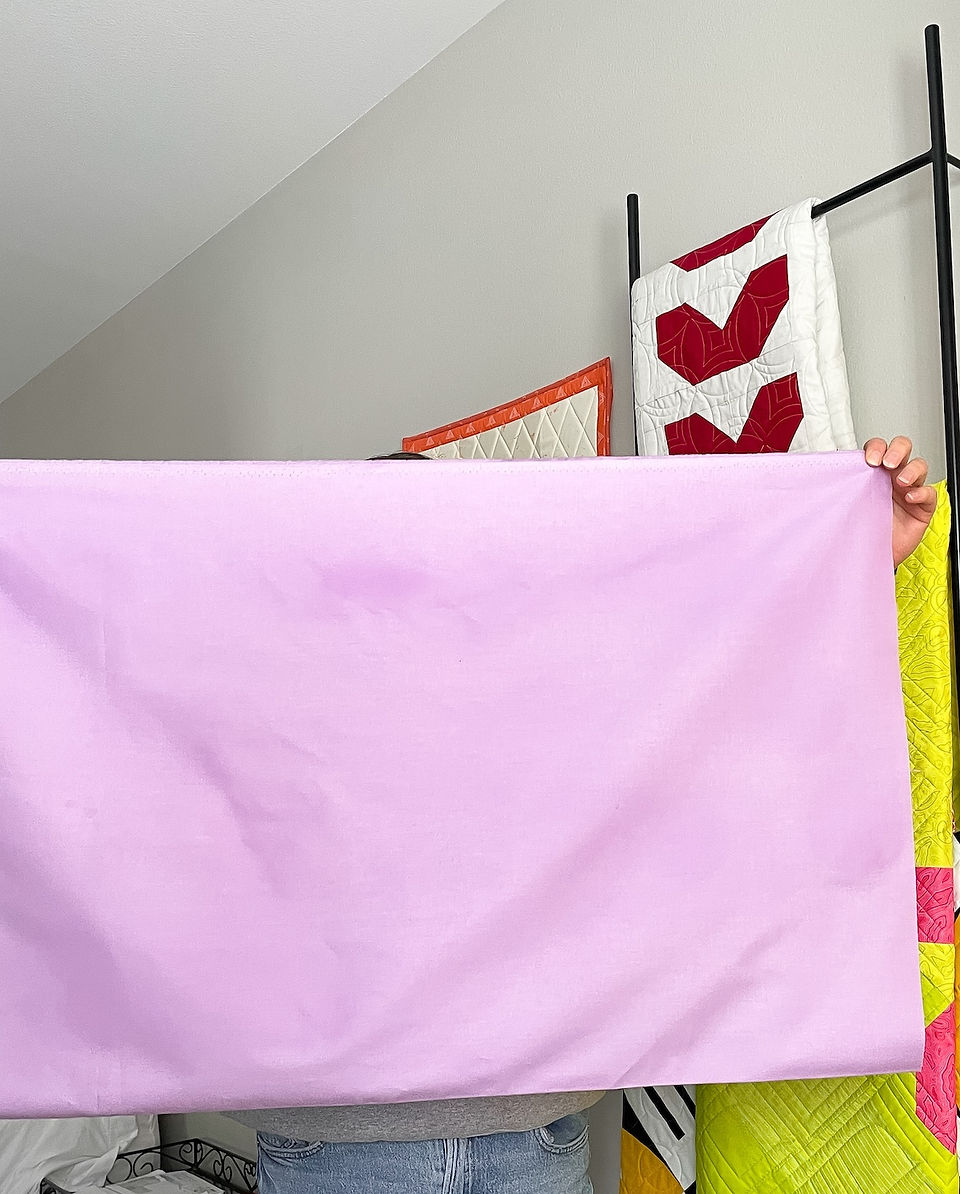 A person holds up light purple fabric 