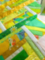 Scraps of yellow and green fabric sewn together in a log cabin style quilt block