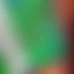 A close up of a multi-colored green quilt with a blue binding and orange and pink backing.