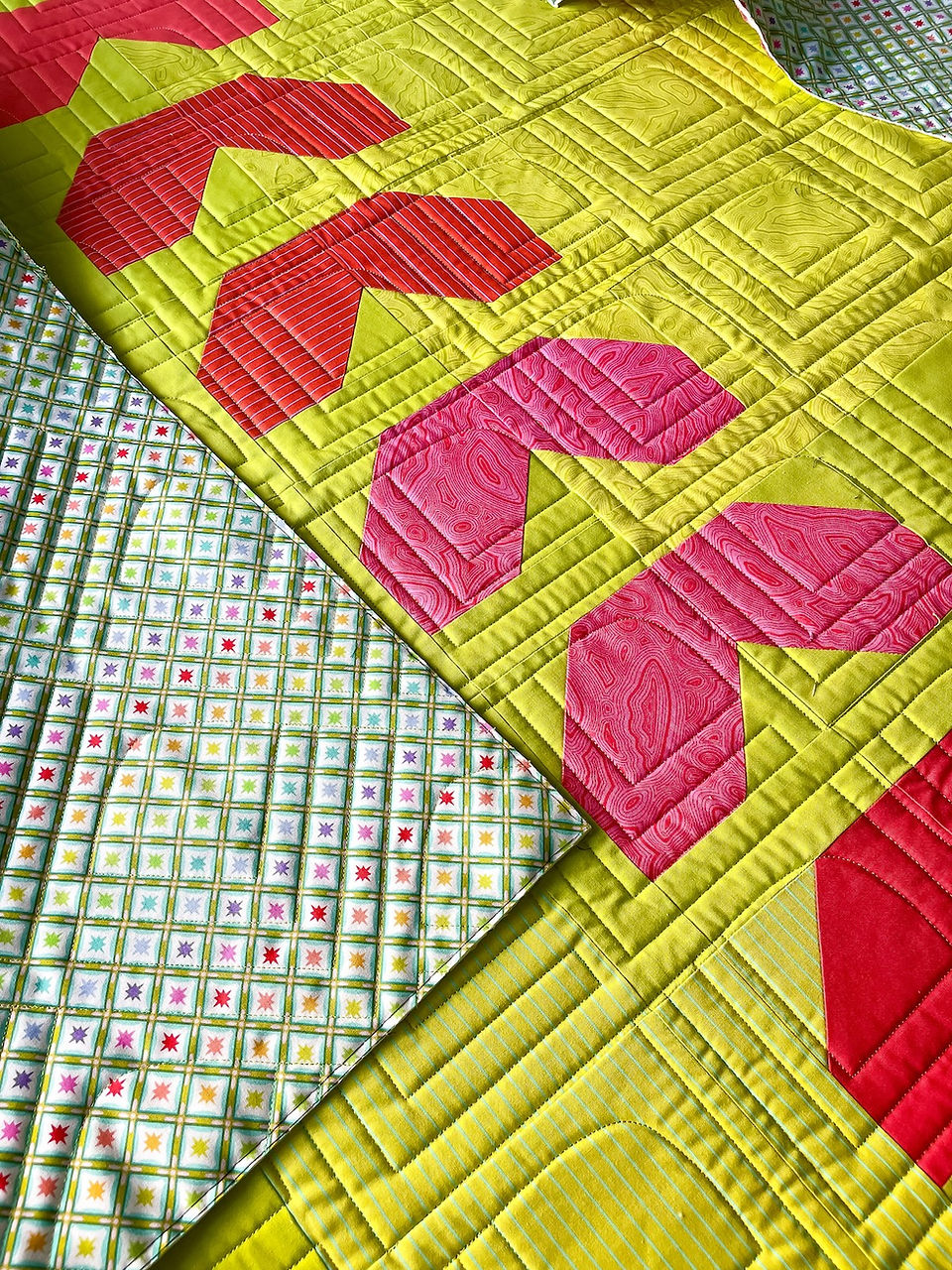 A close up image of a neon yellow and red quilt with softball seams