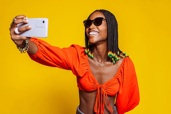 Smiling african woman with braided hairstyle and sunglasses, holds modern mobile phone in 