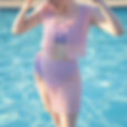 woman modelling crocheted swimsuit coverup skirt and top, in front of pool water