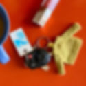 Blue cup, car key with small yellow sweater keychain, "I ♥ ST LOUIS PUBLIC LIBRARY" tag, red background, lipstick nearby.