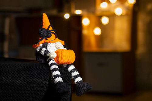 halloween themed gnome holding crochet pumpkin. He's weairng a witch style hat with spider