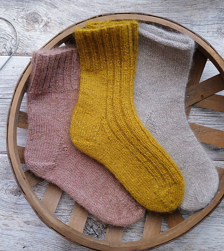 three hand knit socks displayed on wood surface