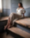 woman modelling cream crochet skirt in flowy top. posing on wooden staircase.