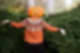 woman modelling which themed knit sweater. model wearing carved pumpkin on their head.