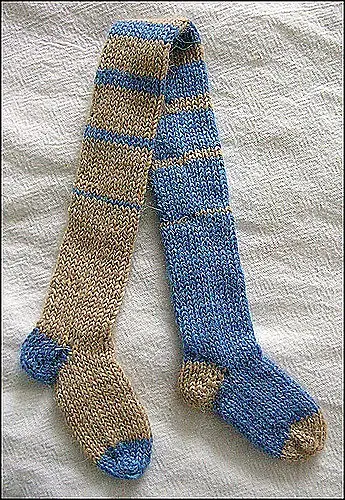 Knitted scarf with blue and beige stripes on a textured white surface, showcasing intricate patterns and cozy, warm vibes.