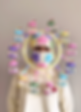 Person wearing a colorful knit balaclava with stars, surrounded by a circular headpiece with mini crochet carousels, set against a plain background.