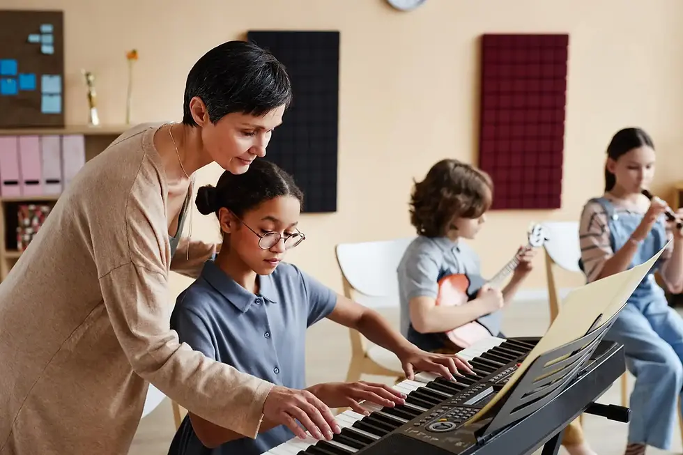 Female teacher guiding young girl playing keyboard in music class.