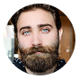 Man with a full beard, mustache, and striking blue eyes headshot.