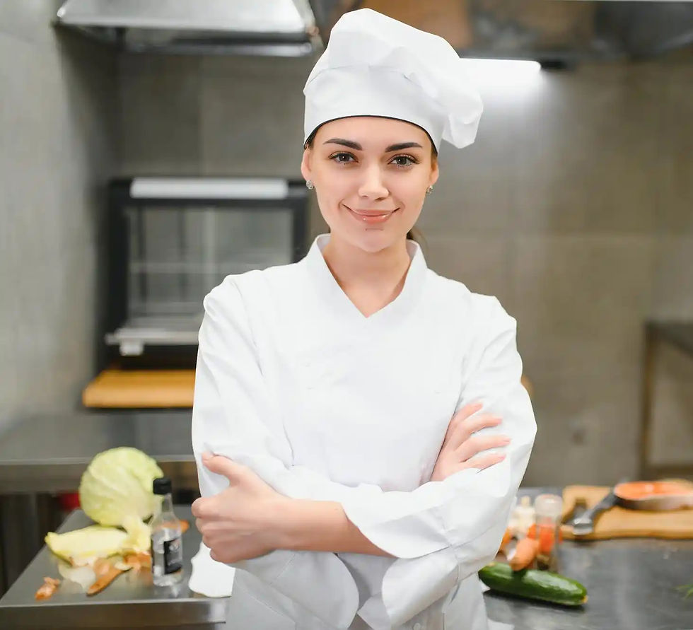 Smiling female chef in white uniform standing in commercial kitchen.