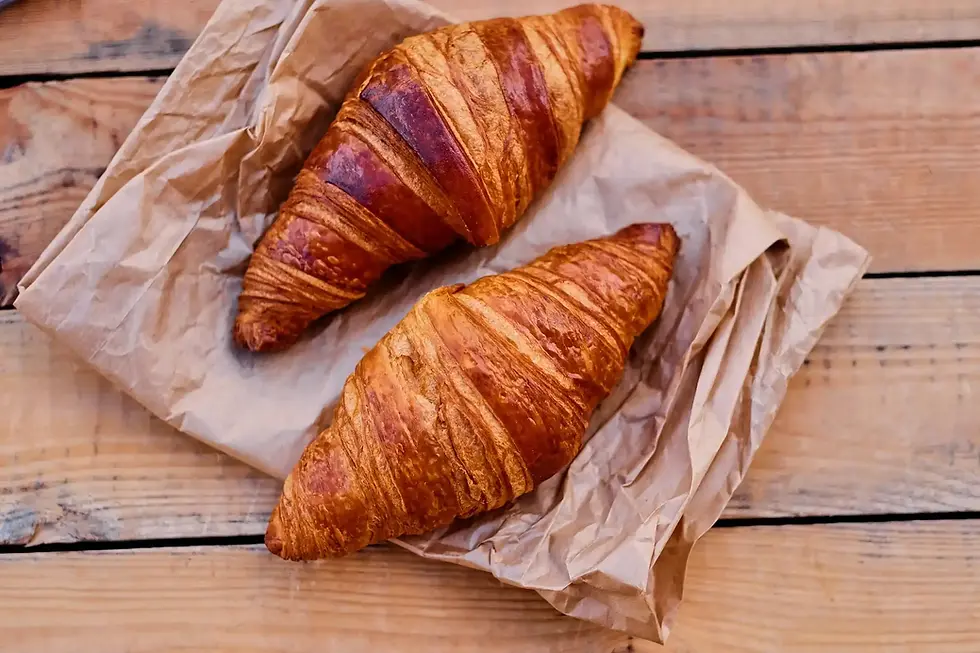 Two golden-brown croissants on paper