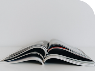 Open magazine with curved pages on a white background, minimalist close-up with soft light.