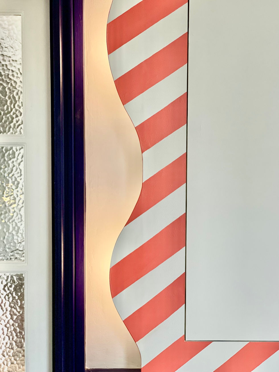 Stripy painted curved cabinet design to store sun glasses and other essentials with hidden lighting