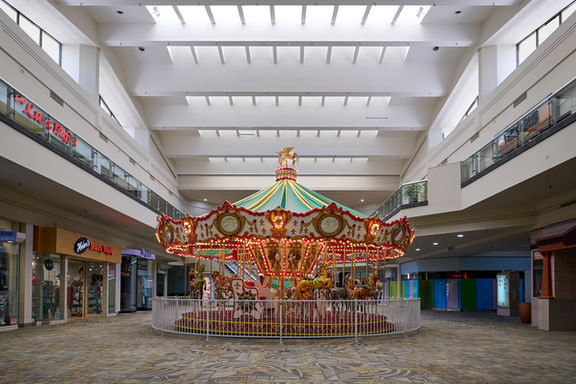 Fine art street photography image a carousel lit up in an empty mall.