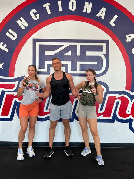 Three athletes pose with drinks at F45 Training.