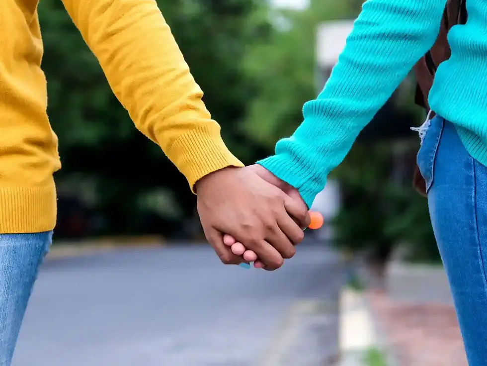 Two people hold hands walking down the street. Optimistic and hopeful image. 