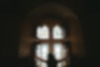 A visitor opens the shuttered windows at Castell Coch, revealing intricate stained glass designs and bathing the room in light.