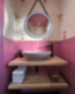 Countertop basin with oak shelf storage and black tap, pink walls and flamingo wallpaper