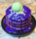 A side by side gallery image showing the "She Draws It, I Cook It" concept. On the left is an imaginative, colorful childhood drawing of purple ube pancakes. On the right is a vibrant, professional photograph of the real life food creation cooked from scratch to perfectly mimic the shape and style of the sketch.