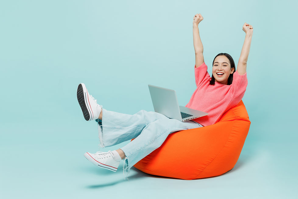 Full body young happy woman of Asian ethnicity 20s in pink sweater sit in bag chair use wo