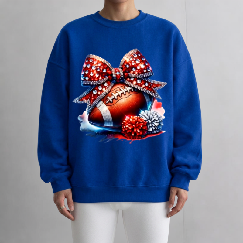 Thumbnail: Bluel sweatshirt featuring a sparkling rhinestone bow above a football with red and silver pom-poms. The design blends sporty