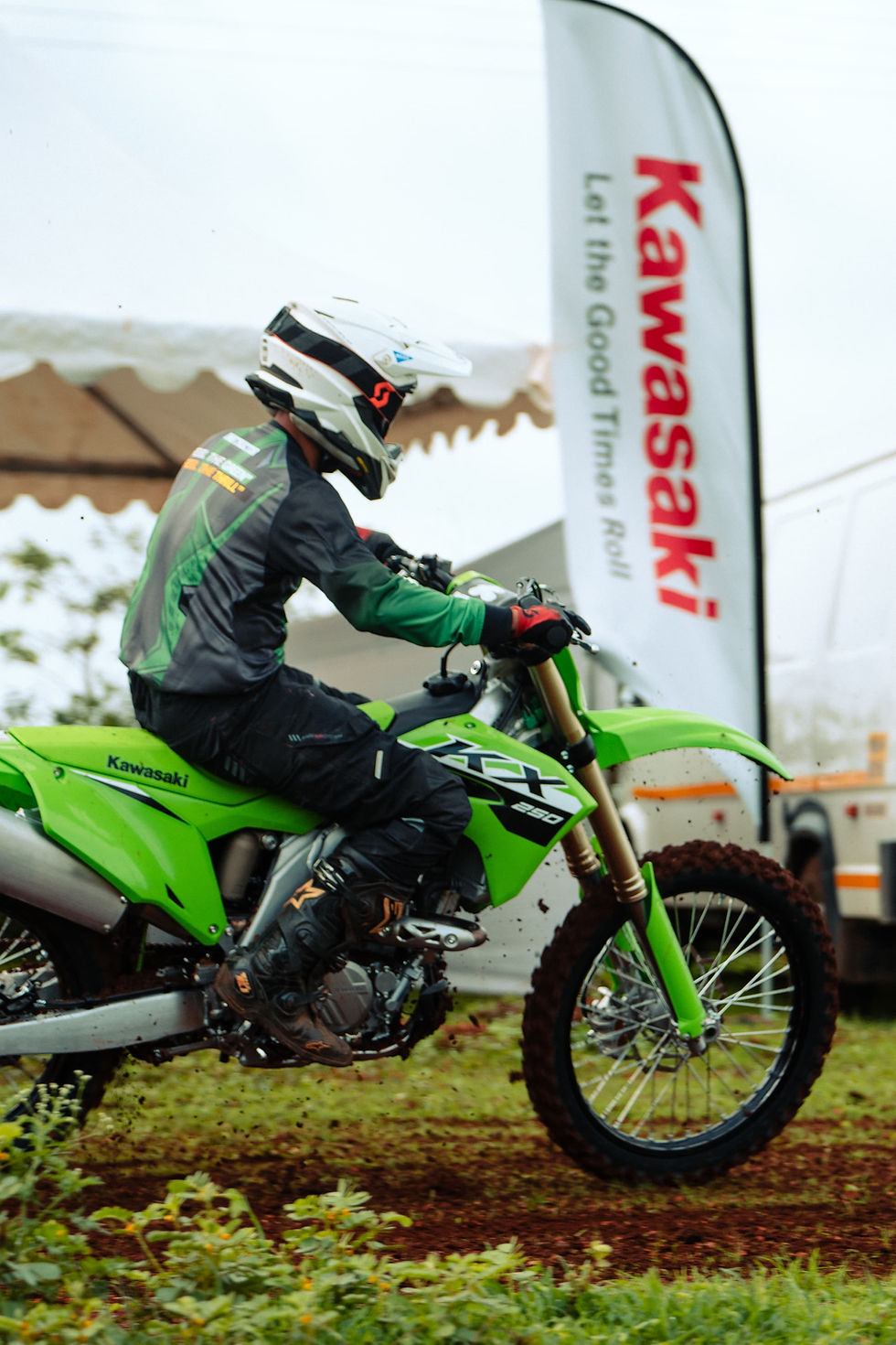 A person riding a green Kawasaki motorcycle, Kawasaki flag reads "Let The Good Times Roll".