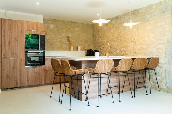 Cuisine moderne avec îlot central et murs en pierre dans un gîte de charme dans le Jura, idéale pour vacances en famille à la montagne