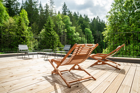 Transats sur terrasse en bois avec vue sur la forêt du Jura au gîte Le Paisible