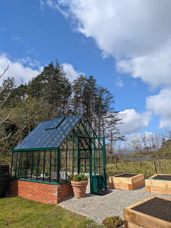 Scenic view - moss green glasshouse set in a lush foresty landscape