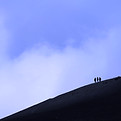 Three hikers ascend a dark, cloudy mount