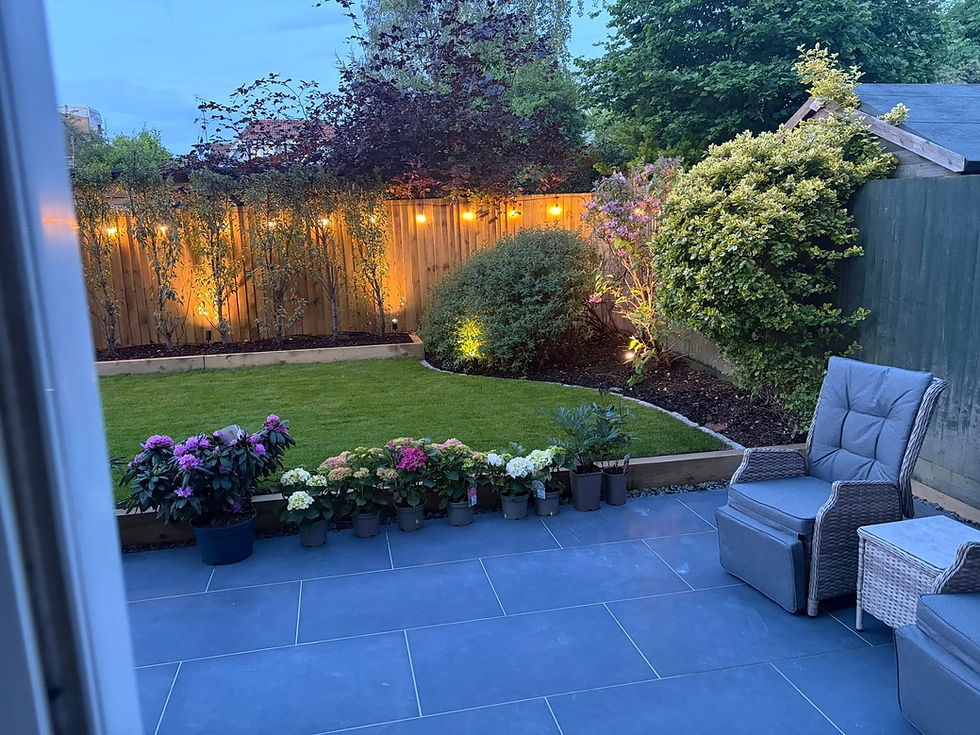 Completed garden transformation in Reading with slate patio, turf, raised planting beds and festoon lighting by JM Landscapes