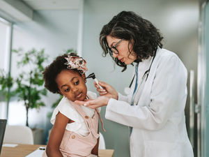 Doctor examines young girl's ear to know what type of ear infection it is