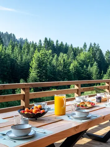 Grande table en bois sur la terrasse du chalet Forest Lodge avec vue sur la forêt vosgienne