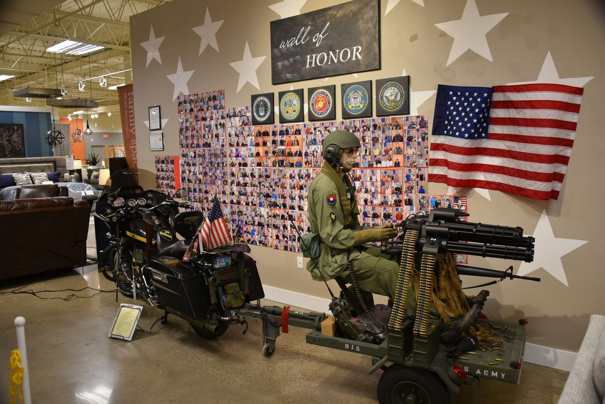 Rear view of a custom-made motorcycle built for a military veteran, towing a small trailer with a mannequin dressed as a soldier and featuring a mounted weapon.