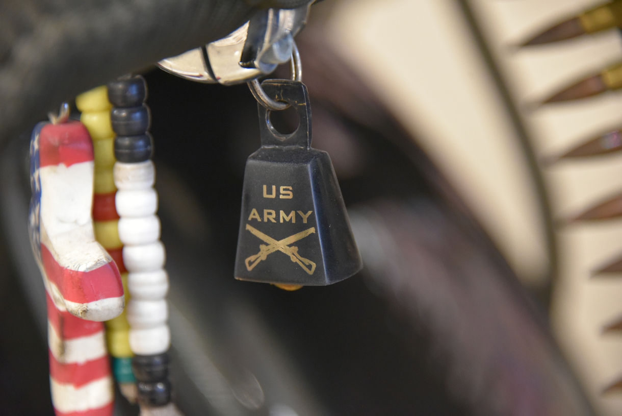 Close-up view of small cowbell displaying U.S. Army insignia with two crossed guns.