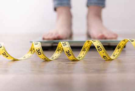 weight loss tape measure on the floor with woman feet standing on scale. Medical Weight loss, semaglutide and tirzepatide