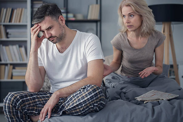 Male and female sitting in bed with male looking disappointed with his poor libido 