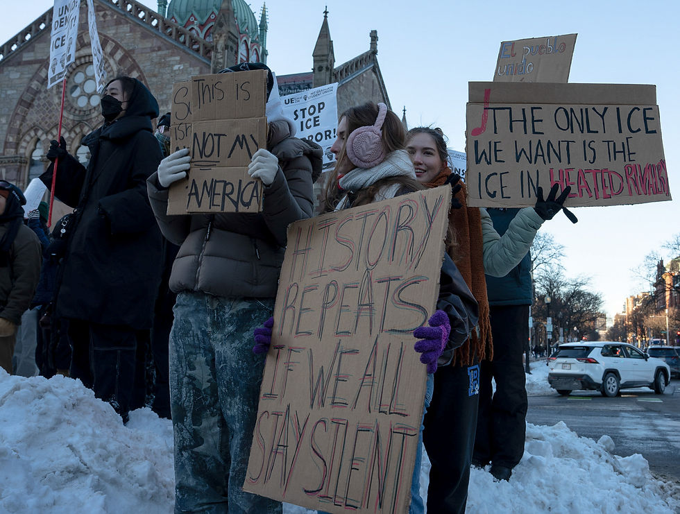 Protesters stand on a mound of snow while holding up homemade signs at Copley Square.