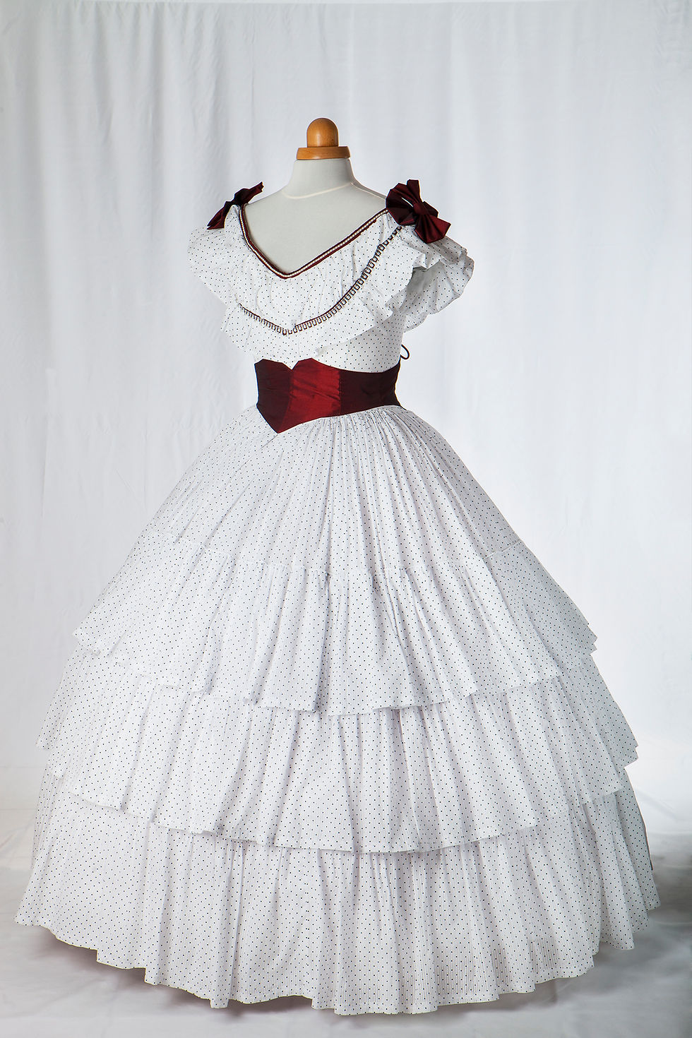 Robe de bal 19e siècle à crinoline en coton blanc à pois noirs avec nœuds et ceinture bordeaux Vue de 3/4 face