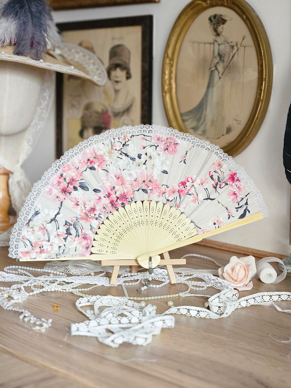 Eventail en satin de coton à fleurs roses et blanches sur fond beige avec armature de bois clair vue de dos